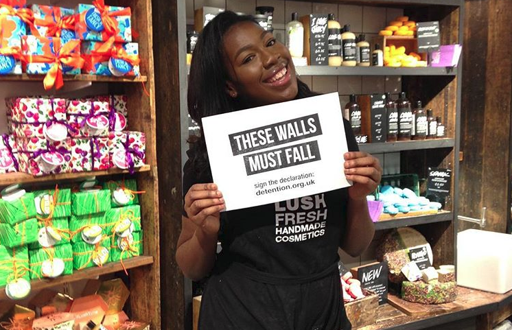 Lush worker with These Walls Must Fall sign