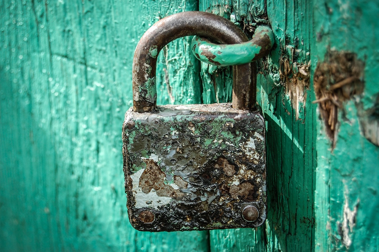 a rusty padlock on a green door