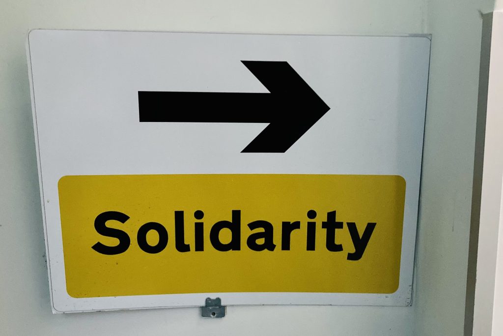 A yellow 'Solidarity' sign with an arrow pointing right