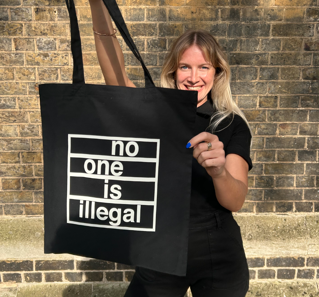 Staff holding the No One Is Illegal tote bag