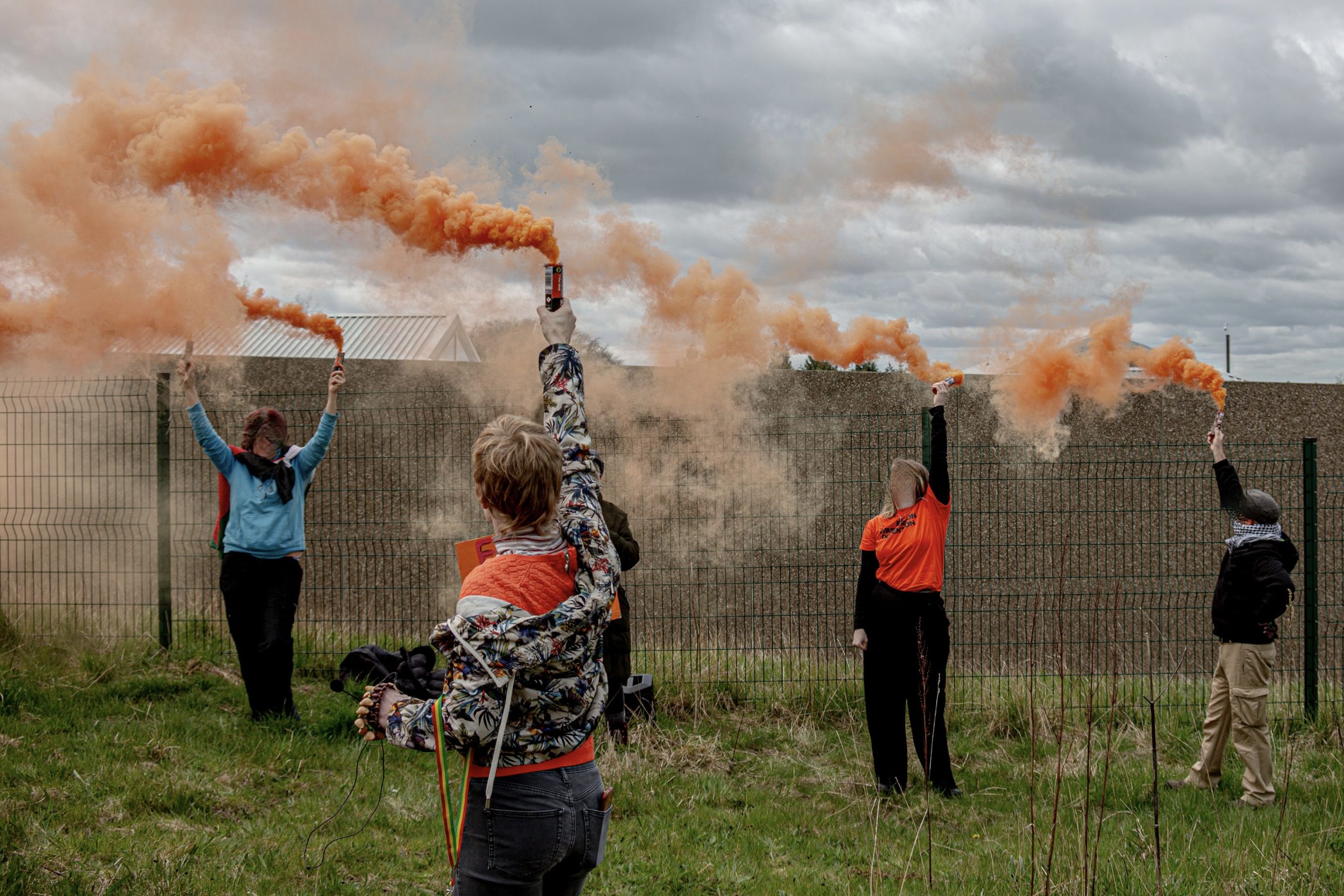 The No to Hassockfield campaigners demonstrating outside the detention centre, holding up smoke flares just outside the fence.