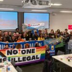 Attendees of the Sheffield event posing and holding up banners that say 'No One is Illegal', 'Solidarity Knows No Borders', and 'Right to Remain'