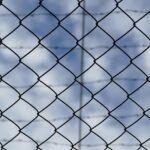 a barbed wire fence against the background of a blue but cloudy sky